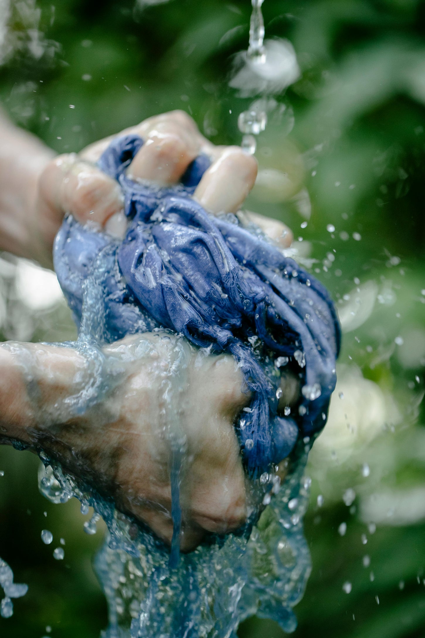 A refined individual cleansing a dyed cloth with flowing water, symbolizing chemical free dyes.